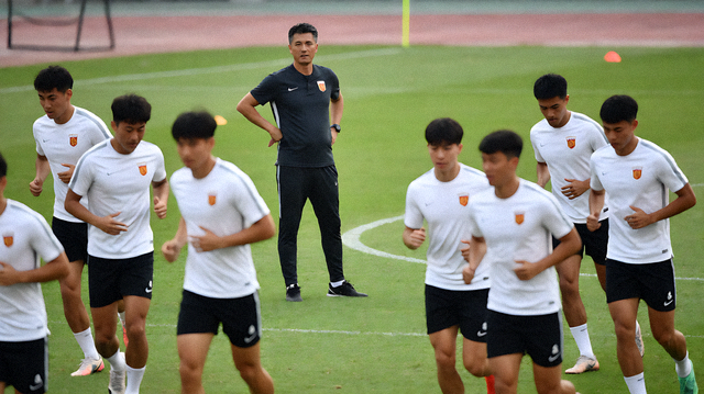 球队在训练场上进行战术演练，教练在场边观察球员跑位